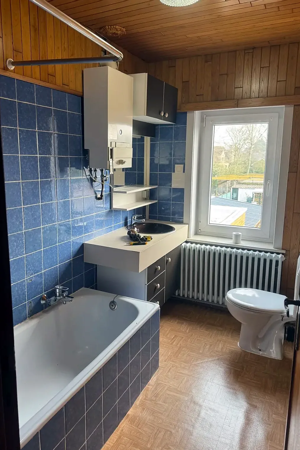 Badkamer met blauwe wandtegels, ligbad en staand toilet